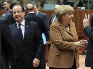 France's President Hollande walks past Germany's Chancellor Merkel during European Union leaders summit in Brussels